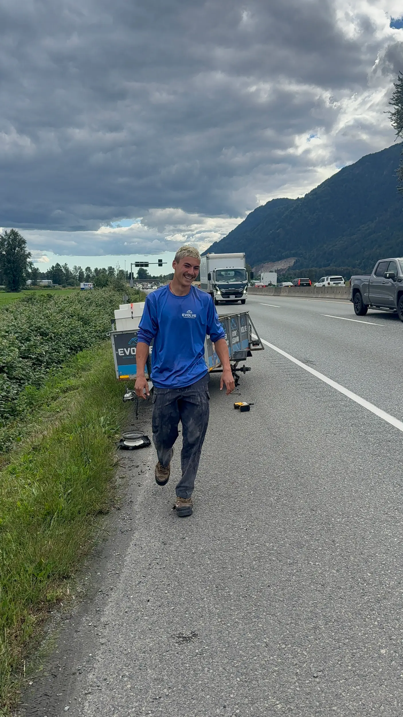 Evolve crew member on a job along a Fraser Valley highway with the mountains behind