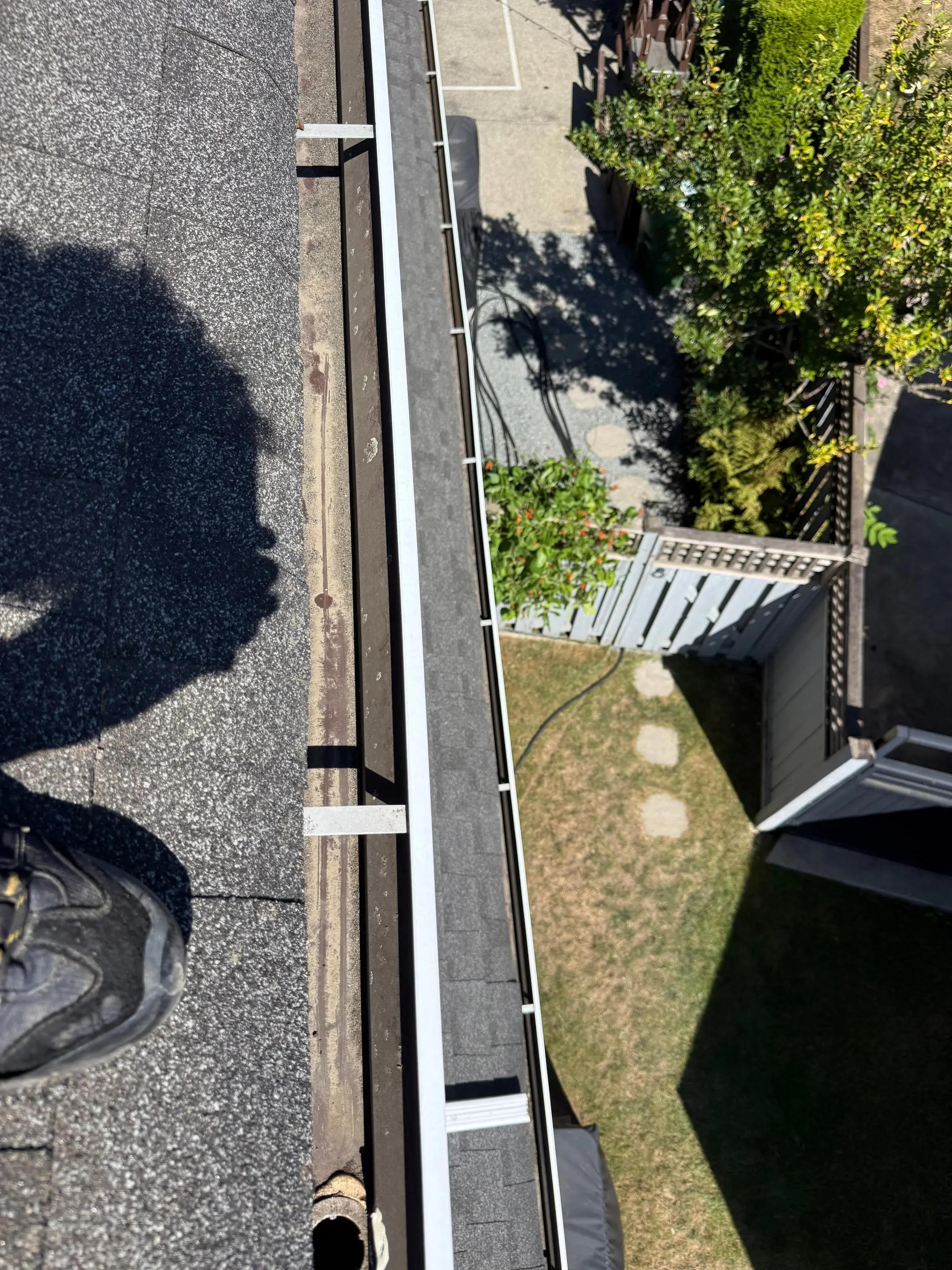 Looking down a freshly cleared gutter run from the roof, with the downspout opening at the far end