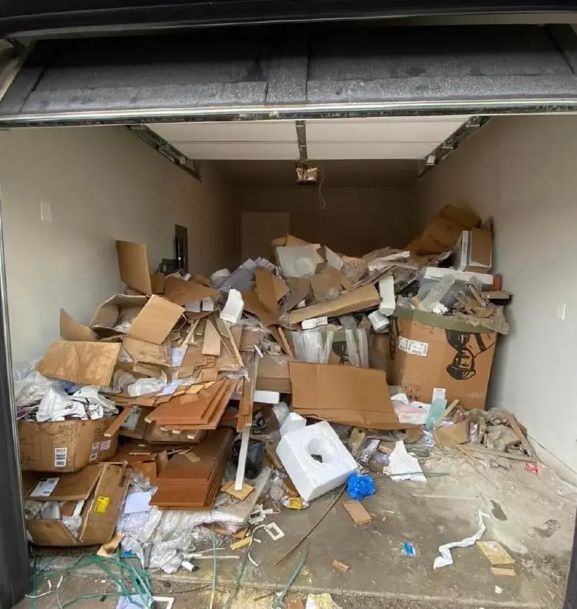 Garage floor buried in cardboard boxes and debris before a clear-out