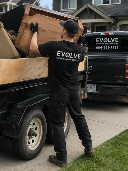 Evolve crew member lifting old furniture into a loaded dump trailer