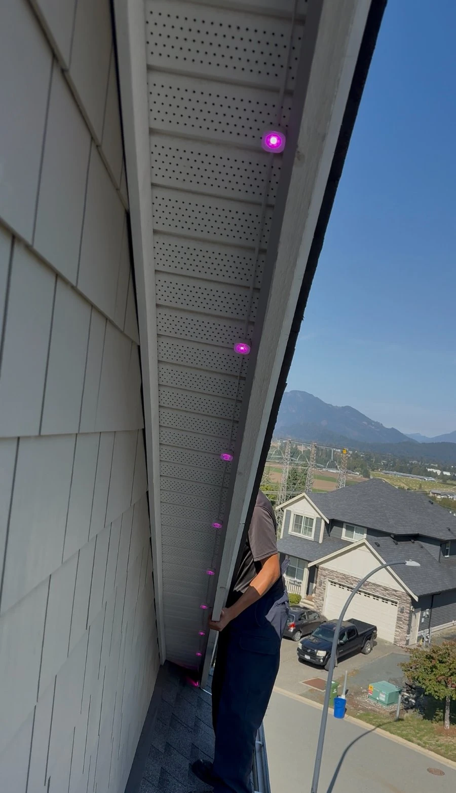 Evolve installer clipping Govee puck lights to the underside of a soffit