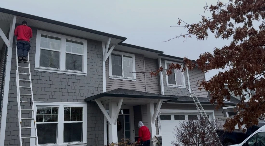 Evolve crew on ladders installing Govee lights on a grey two-storey home