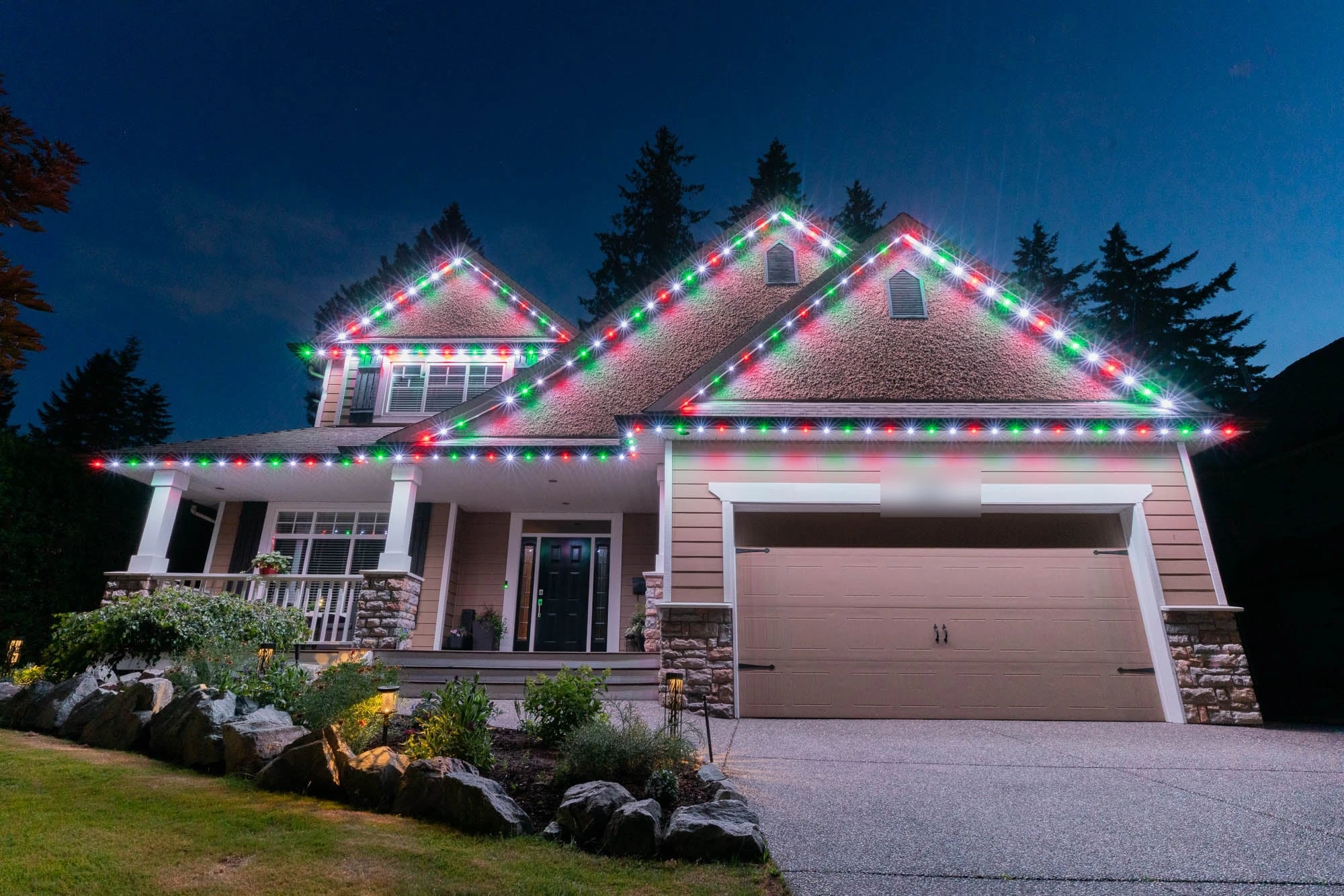 Two-storey home at dusk with red, green and white permanent LED track lights outlining every gable and roofline