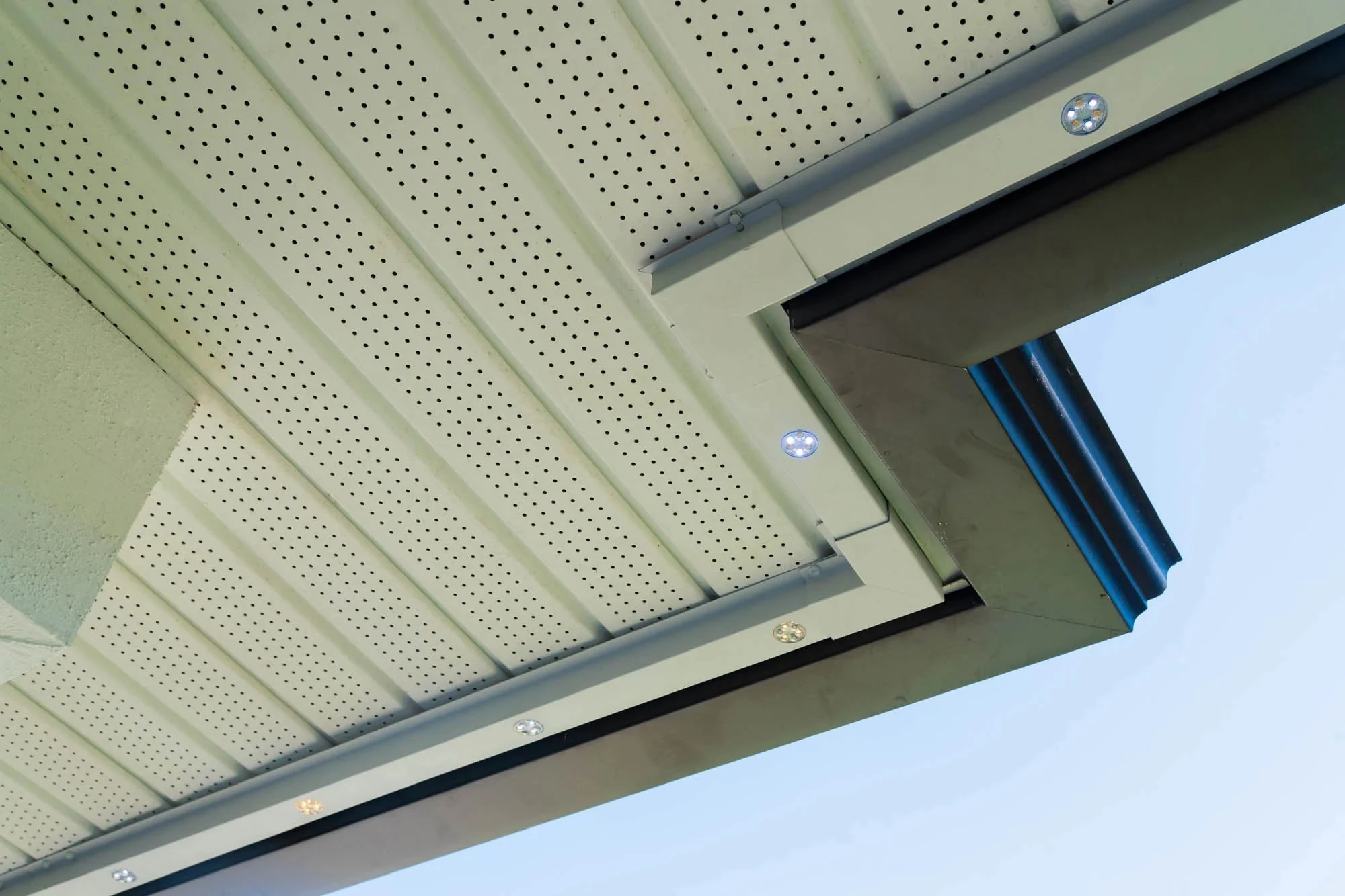 Looking up at a soffit corner where small LED lights sit in a trim-coloured track that turns the corner