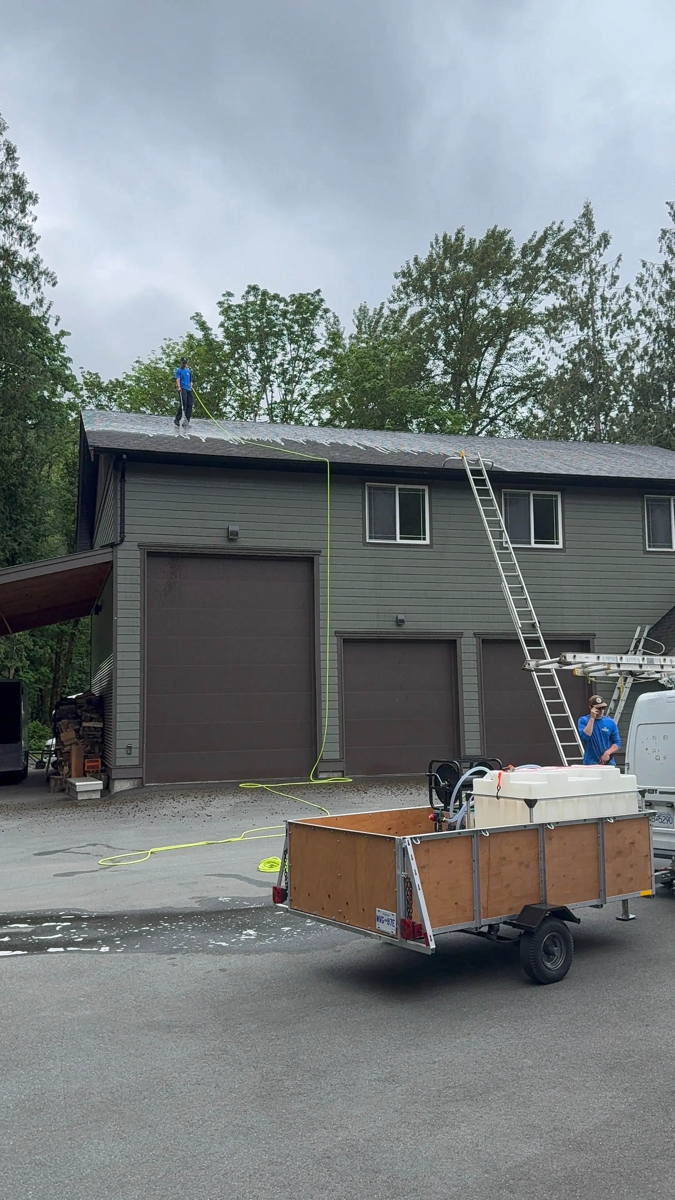 Evolve work trailer and equipment set up in the driveway of a two-storey home, with a ladder against the garage