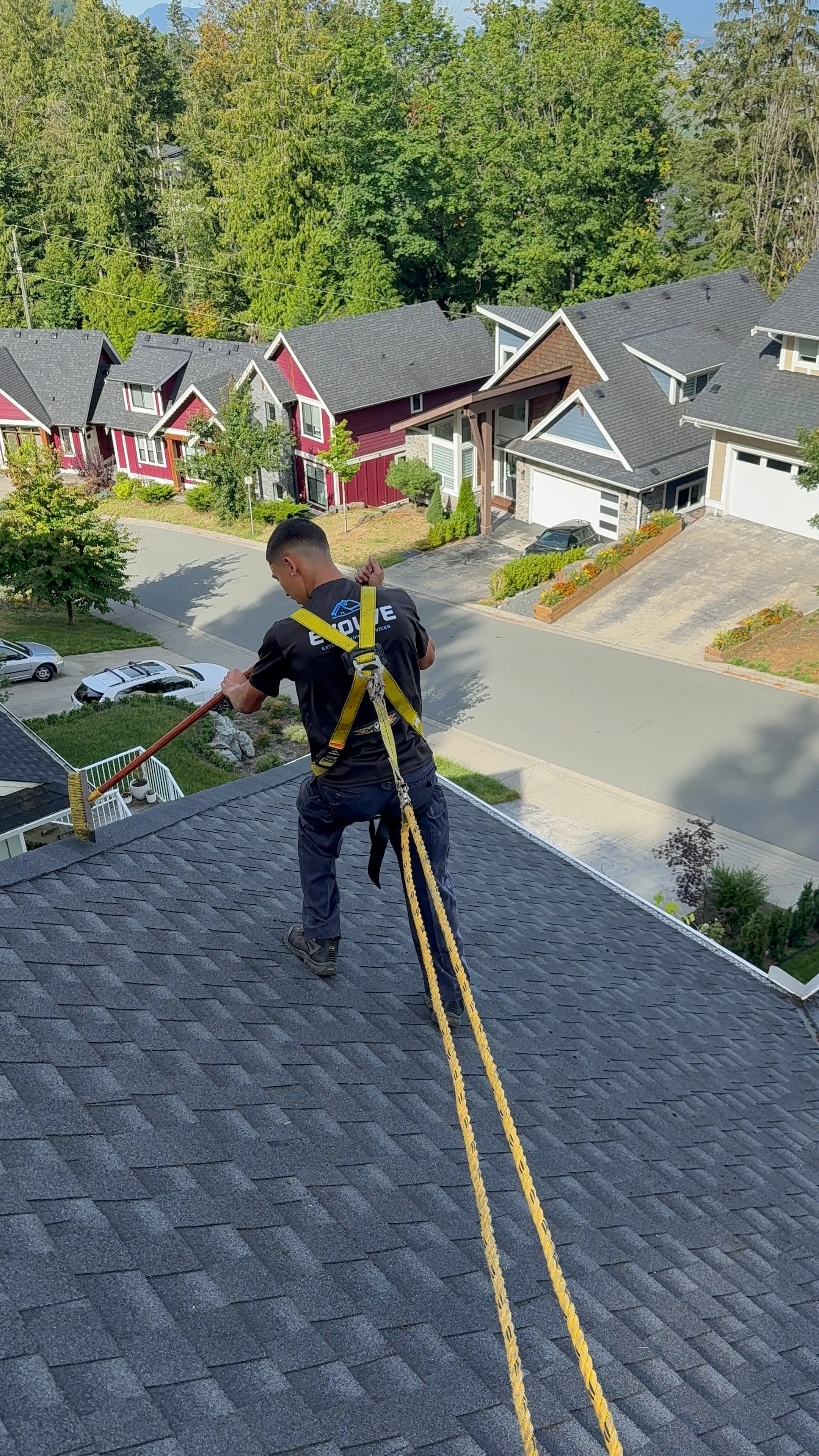 Evolve crew member tied off with a safety rope while inspecting a shingle roof