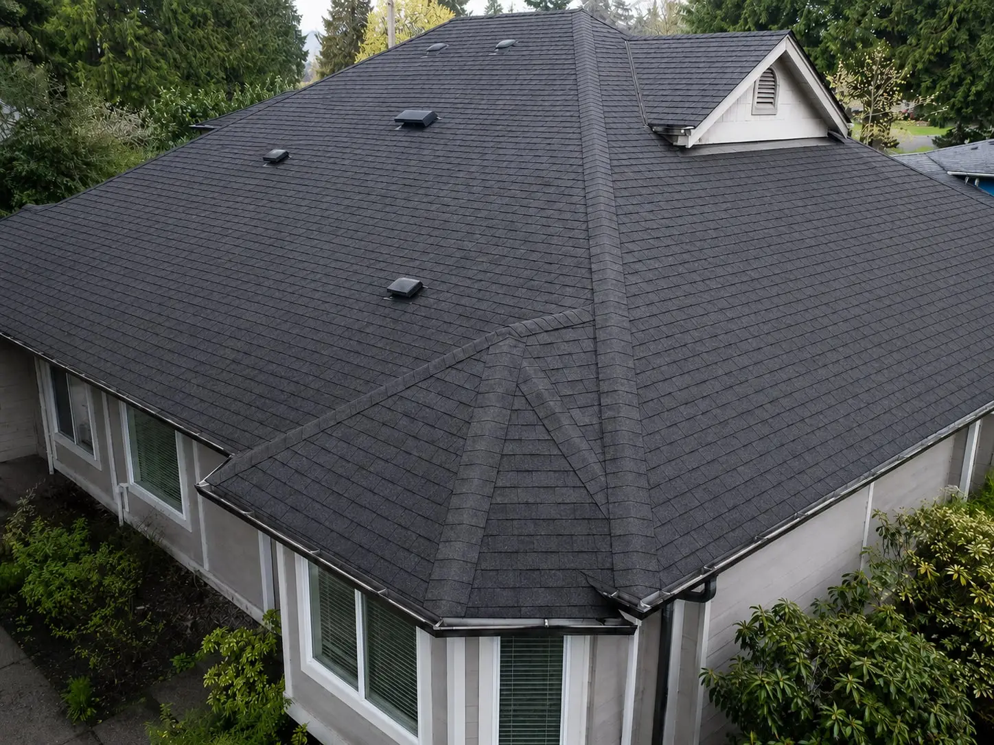 The same hip roof with clean, even charcoal shingles after moss removal and a soft wash