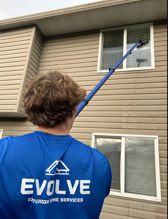 Evolve crew member cleaning an upper-storey window with an extended water-fed pole