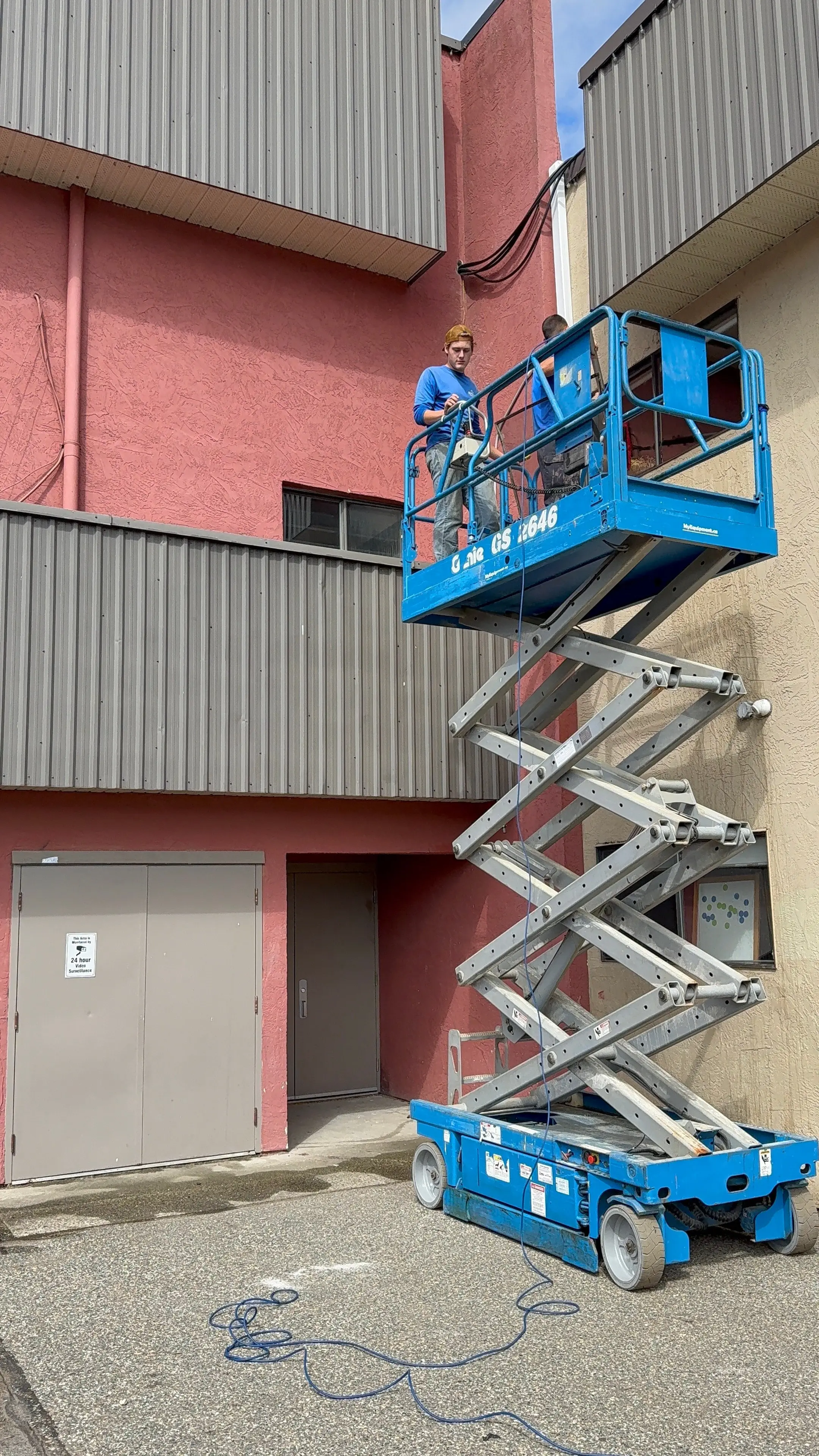 Evolve crew member working from a scissor lift on the side of a commercial building