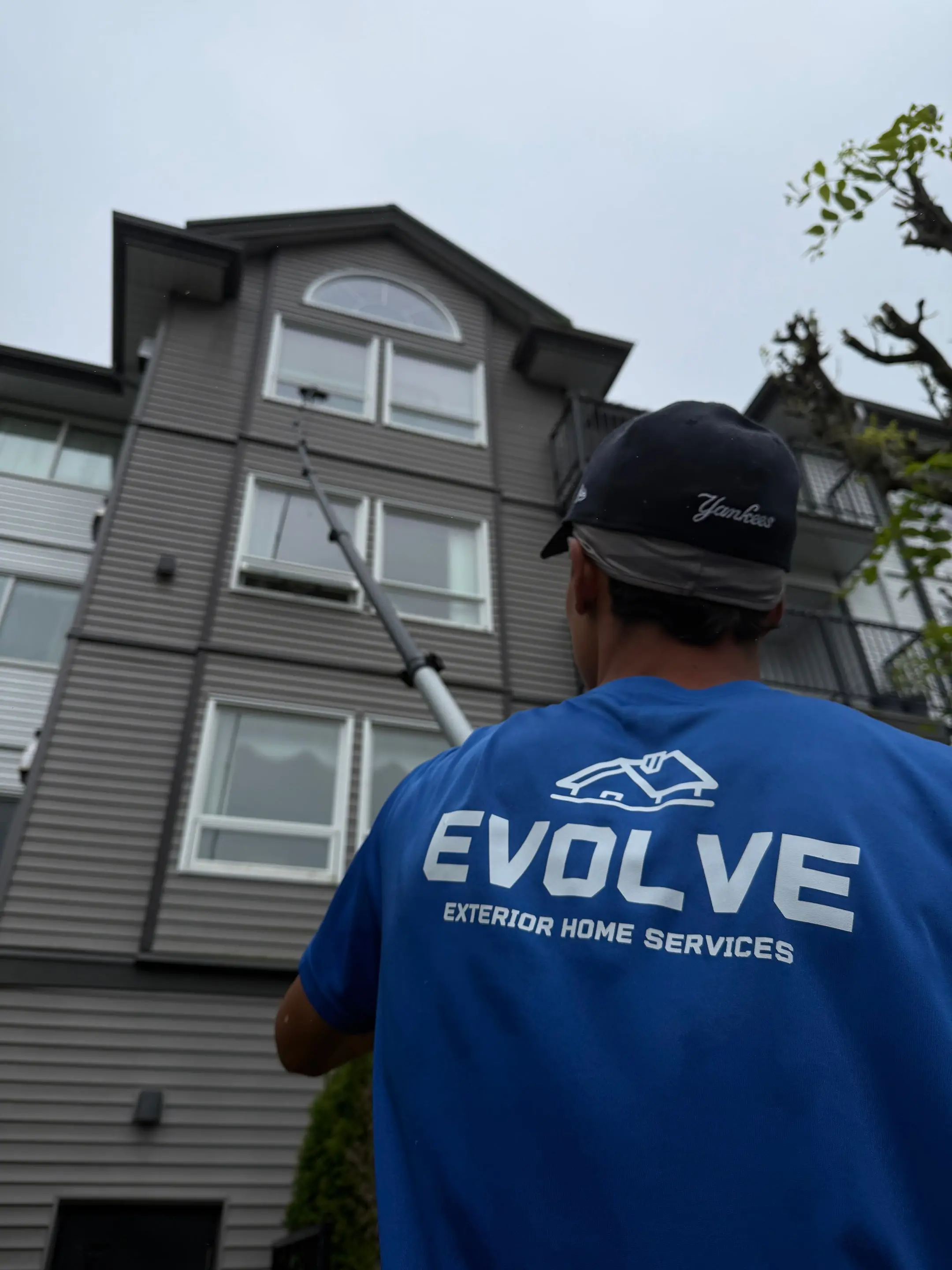 Evolve crew member using an extended water-fed pole to clean windows high up a multi-storey building