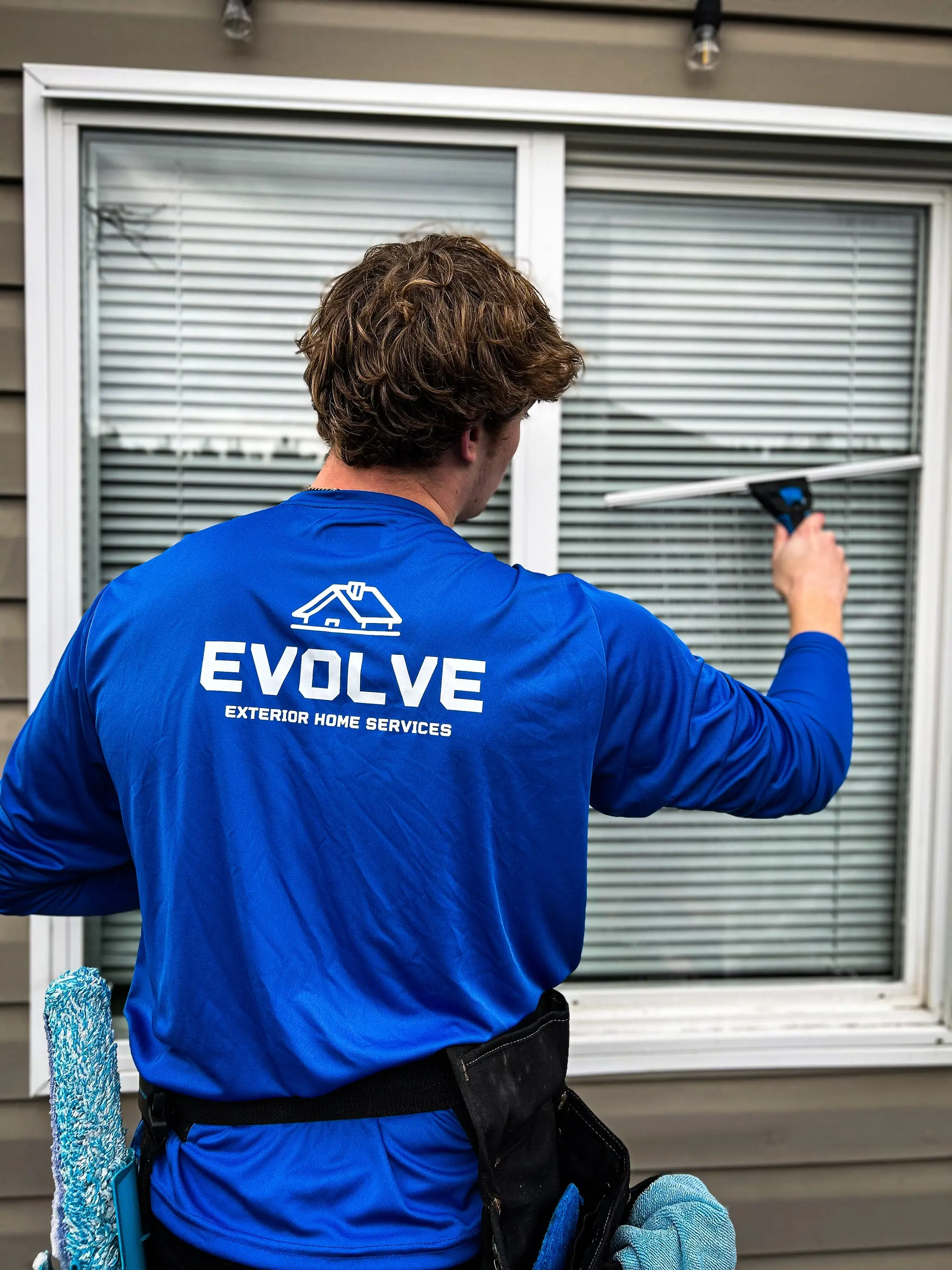 Evolve crew member squeegeeing an exterior window by hand